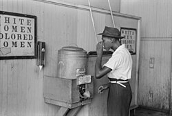 男性有色人種専用の水飲み場で水を飲む黒人男性(1950年代)