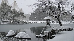雪吊りが施された冬の庭園の風景