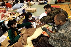 東日本大震災時に学校に設置された避難所でアメリカ軍医の診察を受ける被災者
