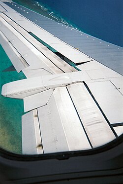 上昇しながら左旋回中の ボーイング737 の左翼。スポイラーが少し上がっている。翼前縁に点状に並んでいるのは ボルテックス・ジェネレーター 。